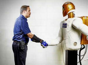 Marty Linn, General Motors manager of advanced technology and principal engineer for robotics, shakes hands with Robonaut 2 (R2), a humanoid robot developed by GM and NASA during a nine-year collaboration that also led to the development of the RoboGlove, an exo-muscular devices that enhances strength and grip through leading-edge sensors, actuators and tendons that are comparable to the nerves, muscles and tendons in a human hand.
